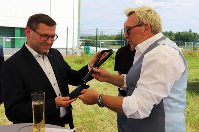 Bauplaner Arne Gorzolla (r.) übergibt Hiolger Scheich, Geschäftsführer des Freiberger Brauhauses, einen Klappspaten zum Start der Bauarbeiten.