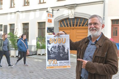 Gert Schmidt von der IG Jazz vor der Alten Mensa mit einem Plakat für das Konzert von Bubu am Donnerstag.