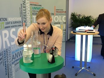 Julia Scholz betreut ein Funktionsmodell. Eine graue Paste liefert den Energieträger.
