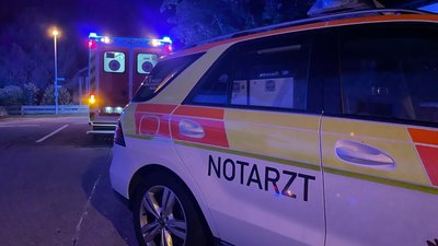 Ein Notarztfahrzeug und ein Rettungswagen parken bei Dunkelheit vor einem Wohnhaus (Symbolbild, keine echte Parksituation). Bei einem Einsatz im Raum Flöha konnte ein Autofahrer die Straße nicht passieren und verwickelte die Rettungskräfte daraufhin in eine Diskussion. 