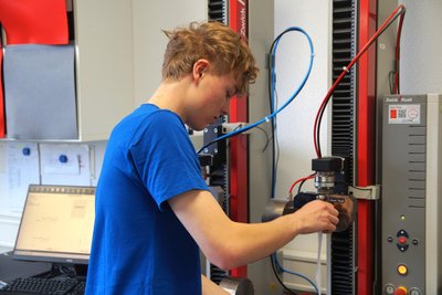 Marten Sachse macht im Erzgebirge eine Ausbildung zum Textillaboranten. An einer Maschine testet er Stoffe zum Beispiel auf Reißfestigkeit.
