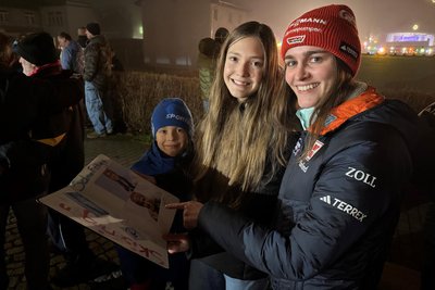 Johanna Kühn (Mitte) freut sich, dass Selina Freitag in dem extra mit Bildern gestalteten Buch unterschrieben hat; links ihr kleiner Bruder Philipp, der die deutsche Flagge zur Begrüßung der Skisprung-Asse auf die Bühne trug.