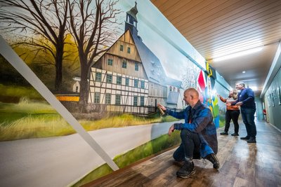 Graffitikünstler Alexander Mehlhorn (l.) beim Gestalten der Fundgrube Wolfgangmaßen, mit Francis Möckel, der Bereichsleiterin Bildung und Programm, sowie dem Geschäftsführer des Kiez Frank Löffler.