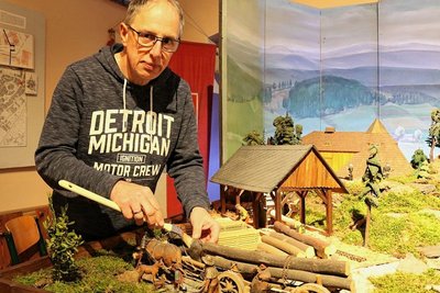 Mario Rudolph, der Vorsitzende des Lößnitzer Schnitz- und Bergvereins, pinselt Staub vom Heimatberg, der ab Samstag in einer Ausstellung wieder zu sehen ist. 