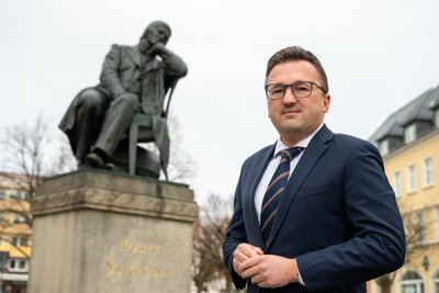 Carsten Körber vor dem Denkmal des Komponisten Robert Schumann auf dem Zwickauer Hauptmarkt. Sein Büro liegt gleich nebenan.