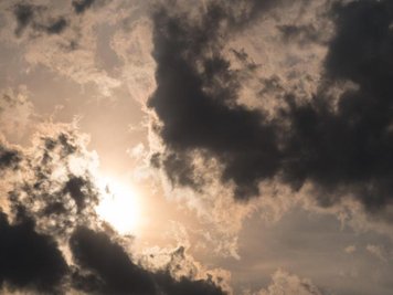 Die Sonne scheint hinter dunklen Wolken.