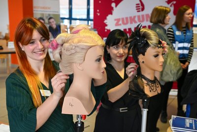 Linda Geißler (links) und Janine Müller zeigen an Puppenköpfen, wie vielseitig der Friseurberuf ist.