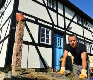 September 2021: Tony Wagner vor dem Fachwerkhaus am Rahmenberg in Hainichen. Derzeit arbeitet er noch an einer Bruchsteinmauer. Für die Sanierung gab es nun den Denkmalpreis des Landkreises. 
