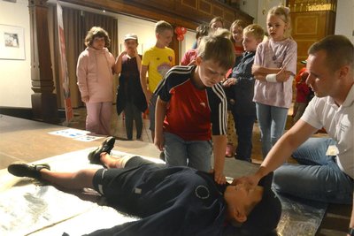 Beim Aktionstag in der Auerbacher Nicolaikirche zeigt Michel Möckel (re.) Emil und den anderen Kindern aus der Treuener DRK-Kita „Märchenland“, wie eine verletzte Person angesprochen und in eine stabile Seitenlage gebracht wird.