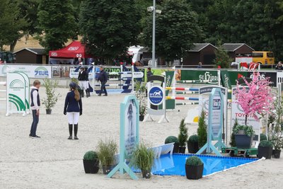 Die Teilnehmer der Zweiphasenspringprüfung Klasse M** laufen den Parcours ab und prägen sich die Hindernisse ein.