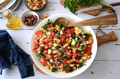 Dieser Salat bringt das Gefühl einer griechischen Taverne auf den Tisch - mit sonnengereiften Tomaten, Oliven, geröstetem Halloumi- und Pita-Würfeln. 