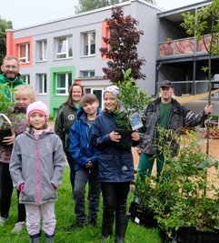 Marko Hofmann von Fielmann; Bianca Beyer, stellvertretende Einrichtungsleiterin des Naturhortes, Jörg Schöne von der Gärtnerei Schöne (hinten v. l.) freuen sich mit Zoe, Chiara, Jonas und Maria (vorn v. l.) über das neue Grün.