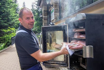 Kellner David Burian aus Karlsbad vom Berghotel Bärenstein betreut den Räucherofen im Freien. Wenn der Geruch nicht schon Appetit macht.
