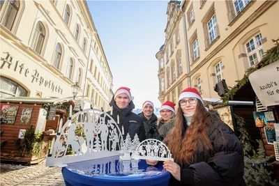 Die Auszubildenden Radael Forner, Hendrik Janka und Victoria Krischik haben am Dienstag gemeinsam mit Ausbilderin Nadine Dorst Schwibbögen aus Metall auf dem Plauener Weihnachtsmarkt verkauft. 