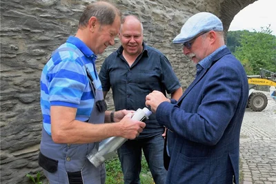 Wolfgang Kühn, Carsten Zeller und Bürgermeister Sandro Bauroth (von links) füllen die Kapsel für die Turmspitze.