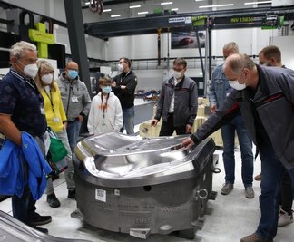 Lutz Kramer (Mitte), Leiter des Werkzeugbaus bei Porsche in Schwarzenberg, und Disponent Detlef Weigel (vorn rechts) führten Gäste während der "Spätschicht" durch die Produktionshalle und erläuterten, wie aus einer Aluminium-Platine ein Karosserieteil wird.
