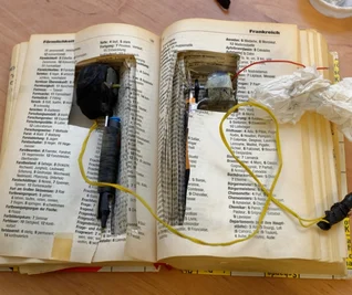 Hohlräume sind das A und O, wenn es um Verstecke auf wenigen Quadratmetern geht: In einem Buch findet zum Beispiel eine Tätowiermaschine Platz (linkes Foto). Drogenspürhund Indy ist in einem Haftraum in Waldheim auf der Suche nach Marihuana (rechts).