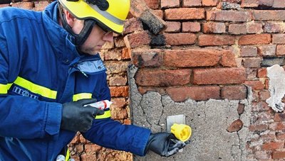 Ein Helfer vom THW Reichenbach bereitet die Messung der beschädigten Hauswand vor. An die Wand werden kleine Spiegel angebracht. Anhand ihrer Bewegung wird ermittelt, wie stabil das Gemäuer noch ist.