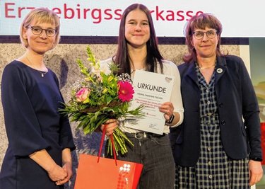 Melina Fabienne Fischer ist zur Eliteschülerin des Jahres 2022 gewählt worden. Oberwiesenthals Schulleiterin Ute Ebell (r.) und Erzgebirgssparkassenvorstand Franziska Herrmann überreichten der Nachwuchsrennrodlerin während der Sportgala in Marienberg Urkunde und Geschenke.