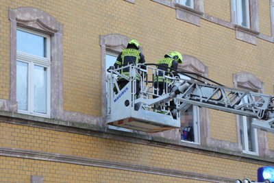 Feuerwehrmänner nähern sich von außen der Wohnung des Mannes.