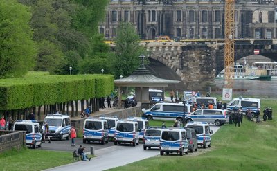 Polizisten stehen mit Einsatzfahrzeugen am Ufer der Elbe.