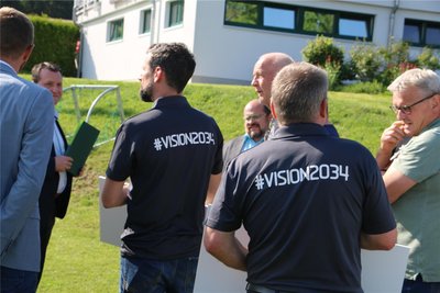 Vision 2034 prangt auf den Rücken der Sportler.