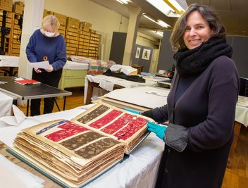 Evelyn Schweynoch mit einem Musterbuch in der Historischen Schauweberei. Die Theaterschneiderin hat Kunstgeschichte studiert und in der Textilsammlung Dresden sowie als Textilkuratorin am Leipziger Grassi-Museum gearbeitet. Im Hintergrund Museumschefin Andrea Weigel. 