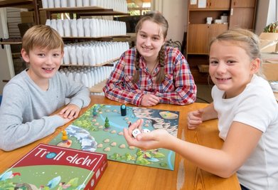 Zwei Würfel und los geht's: Raphaela Haude (Mitte) sowie Felix und Laura Franke probierten das erste fertiggestellte Spiel gleich in der Seiffener Werkstatt von Tino Günther aus.