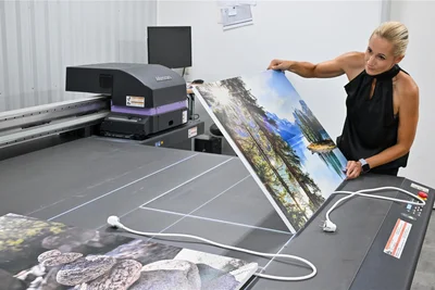 Lucht-Betriebsleiterin Denise Littbarski zeigt am Druckzentrum, wie eine Infrarotheizung mit einer Landschaft bedruckt wird. Die Heizung wärmt nicht nur, sondern ist auch ein Blickfang. Neben Flächenheizkörpern gibt es auch eine Tischheizung fürs Büro oder eine beschreibbare Tafelheizung für Bistros und Küchen.