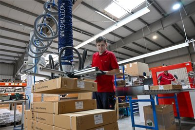 Mitarbeiter Florian Weißbach an einem modernen Hebezentrum beim Verpacken der Elektroheizkörper.