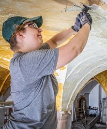 Restauratorin Luisa Tischer von der Firma Lange-Stamm-Lange Restauratoren GbR aus Kaufungen bei der Arbeit mit der Spachtel im Eingangsbereich.