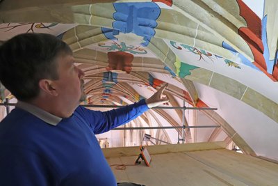 Unter dem Gewölbe des Freiberger Doms bringt Küster Holger Graf die Farbigkeit der Bemalung zum leuchten.