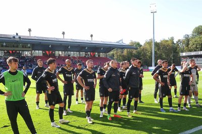 Die Mannschaft des FC Erzgebirge Aue mit enttäuschten Gesichtern vor den mitgereisten Fans.