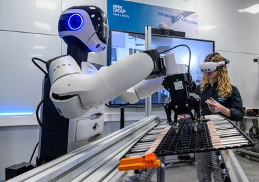 Mitarbeiter trainieren einen humanoiden Roboter für den Umgang mit Bauteilen von Elektroauto-Batterien.
