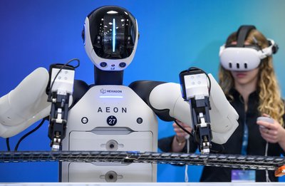 Ein Mitarbeiter weist einen humanoiden Roboter in einen neuen Arbeitsschritt in der Batteriemontage ein.