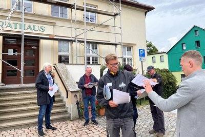 Vor dem Rundgang teilt Julian Helwig (3. v. l.) Pläne mit den Stationen des Rundganges aus. Links Bürgermeister Frank Lohr.