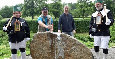 Der Bergmannsstein am Geologischen Lehrpfad im Zechengrund ist nun offiziell eingeweiht. Mit einem Schwapp Sektgetränk vollzieht Mike Glöckner den symbolischen Akt. Künstler Rolf Büttner verfolgt das Geschehen, welches von Carmen und Dietmar Sehm im Habit der Bergleute "Reicher Segen Gottes Sachsenburg" begleitet wird. 