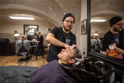 Der „Hair-Schneider“ und Barbier Martin Schneider mit Kunde Joel Wittig, hinten Friseurin Katja Hagen.