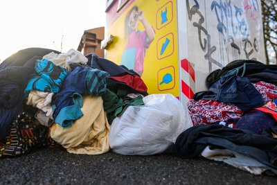 Gebrauchte Kleidungsstücke liegen vor einem Sammelcontainer für Altkleider: Manche Kommune im Erzgebirge steht schon ohne derartige Behälter da.