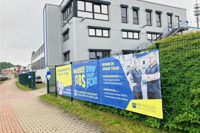 Werbeplakate neben dem Eingangstor zu PTF Pfüller weisen auf den Tag der offenen Tür und auf offene Stellen hin.
