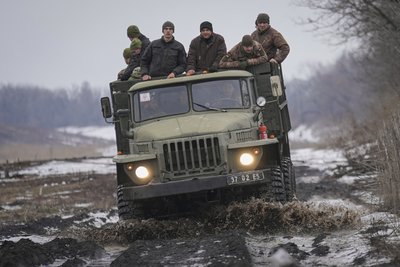 Ukrainische Soldaten stehen auf der Ladefläche eines LKWs, der auf einer schlammigen Straße fährt. Der Aufmarsch russischer Truppen an der ukrainischen Grenze sorgt im Westen seit Wochen für Ängste vor einem möglichen Angriff Moskaus auf die Ukraine, was der Kreml dementiert. 