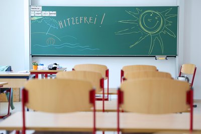 An der Tafel einer Grundschule steht „Hitzefrei!“ (gestellte Szene).