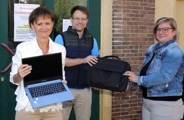 Antje Döbler (rechts), Finanzchefin im Rathaus von Grünhain-Beierfeld, übergibt die neuen Laptops an Schulleiterin Katrin Müller und Lehrer Patrik Sonntag. 