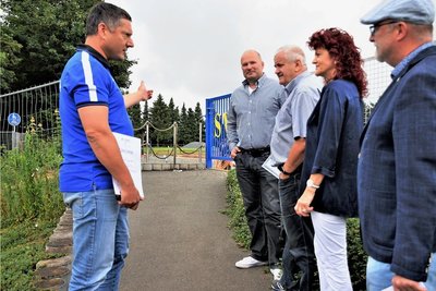 Ronny Röder, Vereinsvorsitzender des SV Coschütz, zeigt Frank Bilz vom Leader Regionalmanagement und der Vorsitzenden der Lokalen Aktionsgruppe, Andrea Jedzig, die Fläche, auf der die Tafel aufgestellt werden soll. Am Ende des Weges entsteht gerade die neue Begegnungsstätte für den Ort. Außerdem im Bild: Sandro Bauroth (rechts), Bürgermeister von Elsterberg, sowie Andreas Oberlein. 
