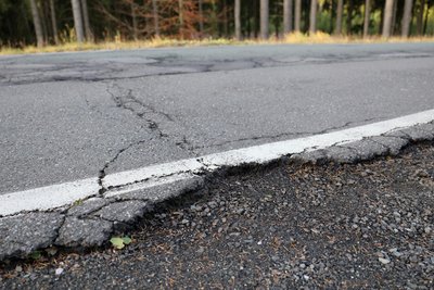 Das Bankett der Straße ist an vielen Stellen eingebrochen, die Straße von Quer- und Längsrissen massiv durchzogen.