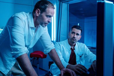 Szene aus „In aller Freundschaft“: Dr. Kai Hoffmann (Julian Weigend, links) und Dr. Ilay Demir (Tan Caglar) machen sich Sorgen um Maria Weber. Diese ist bei einem gemeinsamen Ausflug mit Kai gestürzt.