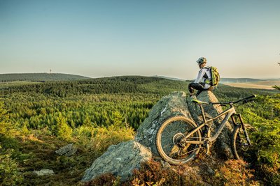 Biken ist im Erzgebirge ein Genuss – hier ein Blick vom Wirbelstein (Tschechien) über den Erzgebirgskamm, rechts am Horizont der Fichtelberg.