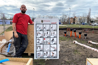 Carsten Kittner (33) baut am Dienstag die Fitness-Geräte für den neuen Outdoor-Park auf. Auf dem Schild sind ein Teil der möglichen Übungen abgebildet, auf der Rückseite noch mal so viele.