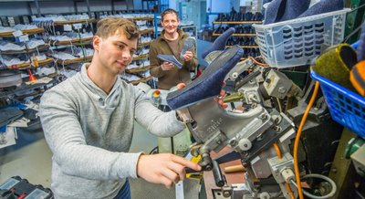 Zeigt her eure Schuhe: Manuel Schürer an der Maschine, mit der die Kunststoffsohlen auf die Schuhe gespritzt werden. Geschäftsführer Kai Schürer (hinten) mit einem Paar der neuen Pantoffeln. 