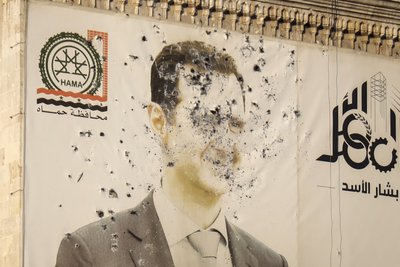 Ein Bild des syrischen Präsidenten Baschar al-Assad, durchlöchert von Kugeln, ist auf der Fassade des Büros der Provinzregierung nach der Übernahme der Stadt Hama durch Rebellengruppen zu sehen.
